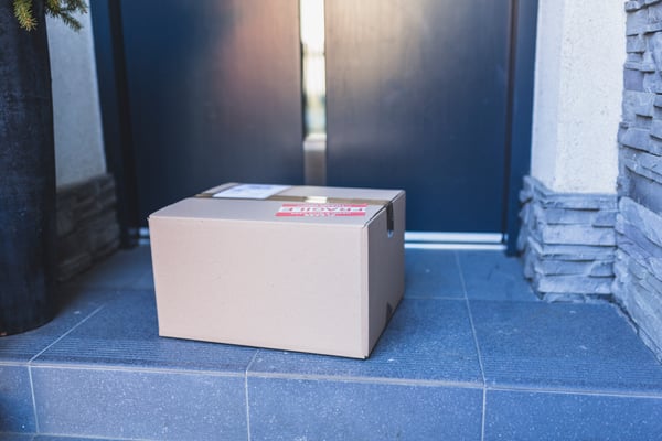 A box at a front door of a house, representing the ending of the order fulfillment process, resulting in customer satisfaction.