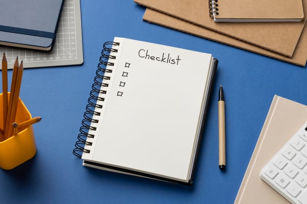 The picture of a notebook on a blue table, open in a page where is written "Checklist" and some checkboxes, representing the steps that you must follow before starting direct exporting to a foreign country.