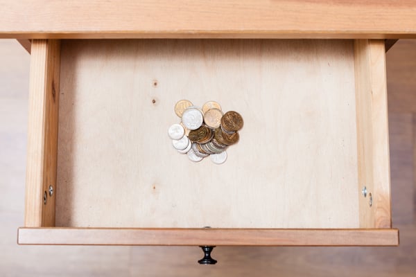 A light wooden drawer with several coins in the center, representing a high-interest savings account