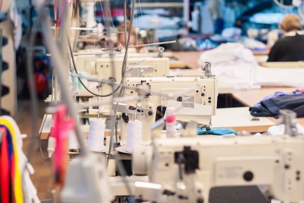 A clothing manufacture filled with fabrics and sewing machines representing the costs of starting a clothing brand.