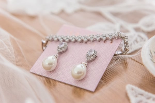 Photo shows a pair of pearl and diamond earrings next to a diamond bracelet from upclose, illustrating how quality jewelry photography can help sell jewelry online.