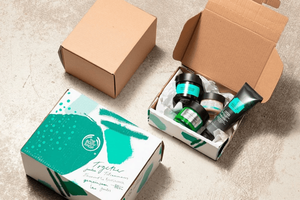 3 boxes of the brand The Body Shop, with one open and filled with cosmetics, with colors and shapes used by their brand, representing how order fulfillment can impact customers' experience.