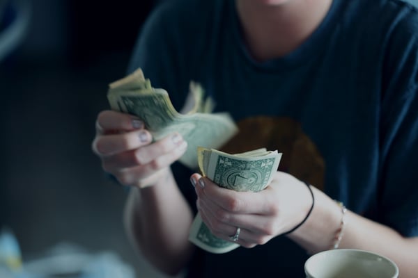 Photo from blog post on passive income ideas shows woman holding cash and counting it