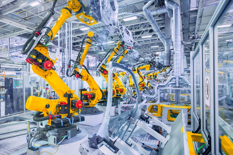 A factory filled with yellow robot arms and machinery representing product development.
