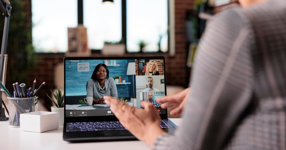 Photo is being used as a cover image for the article on how to start an online business in Canada. In the photo, there is a person sitting at a desk at home, in front of a laptop. On the laptop screen, there is a video call in progress with four other people. 