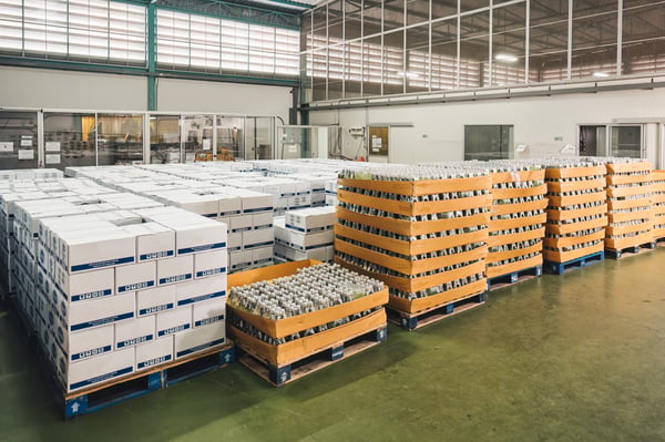 A warehouse with pallets filled with products in bottles and boxes, representing the supply chain management.