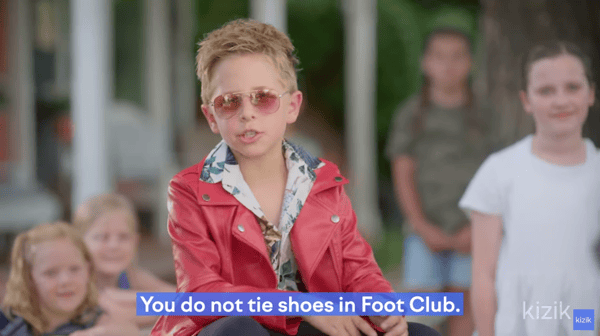 Frame from the Kizik ad shows a kid dressed up like Tyler Durden, and the words You do not tie shoes in Foot Club on the screen, to illustrate the difference between target market vs target audience.