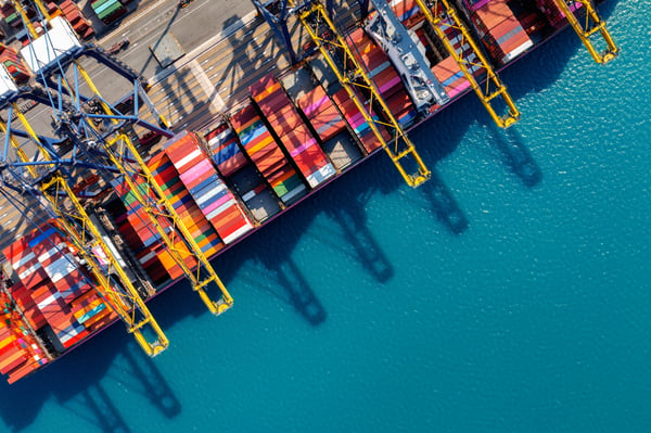 The top view of a ship in a port, filled with colorful containers, representing the question what is logistics