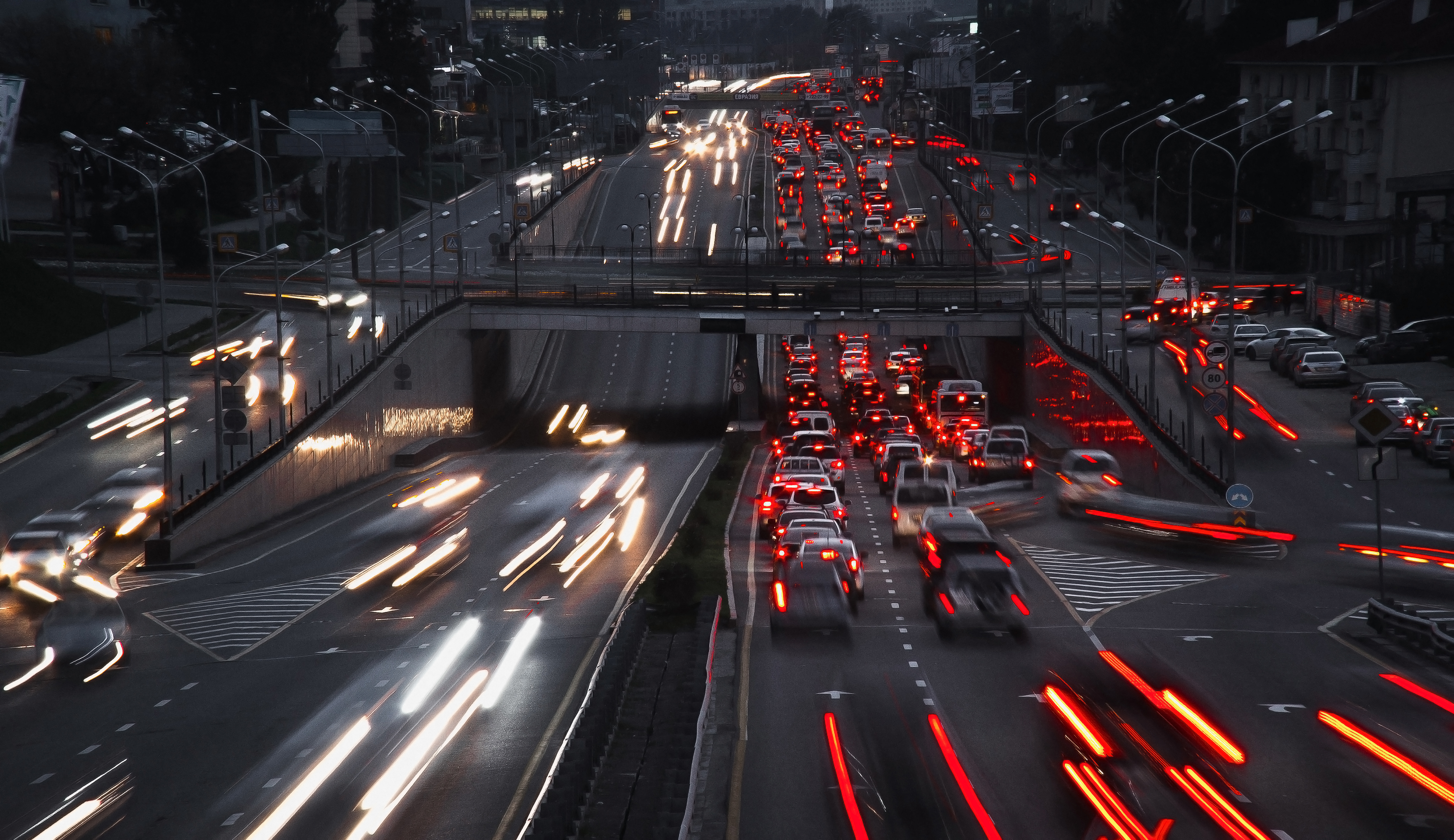 Photo that illustrates blog post on paid traffic shows a busy two-way highway, photographed from above. The headlights and tail lights of the vehicles are blurry, indicating that they are driving at a high speed.